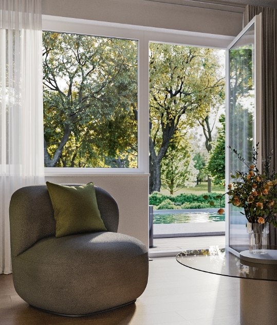 Ein eleganter, grauer Sessel und grünem Kissen vor einer großen Fensterfront.